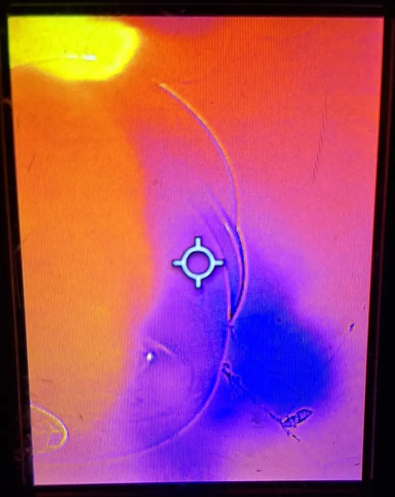 Scherm van een warmtebeeldcamera met een koude plek op de muur bij het zoeken naar een lekkage.